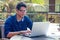 Handsome and successful indian man in a stylish well-dressed freelancer working with a laptop on the beach.freelance and