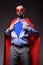 handsome super businessman in mask and cape showing blue shirt