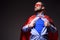 handsome super businessman in mask and cape showing blue shirt and looking away