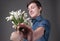 Handsome surprised and smiling young man taking bouquet of snowdrops