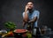 Handsome tattooed male in blue shirt leaning on a blender in kitchen