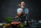 Handsome tattooed male in blue shirt leaning on a blender in kitchen