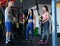 Handsome tattooed trainer explains to two young girls how to do the exercises correctly with functional loops in the gym