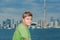 Handsome teenage boy standing against blue Toronto city lake view background on sunny warm day