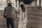 Handsome texas cowboy man in white hat holding hands with beautiful gypsy woman in white dress, couple walking in the city