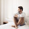 Handsome thinking man in bedroom interior.