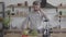 Handsome thoughtful good-looking man in the shirt standing at the table with a blender preparing to make a vegetable