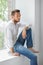 Handsome thoughtful man relaxing on window sill