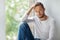 Handsome thoughtful man touching his hair relaxing on window sill