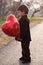 Handsome three year old boy with red heart balloon