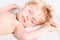 Handsome toddler boy with blond hair sleeping on white bad