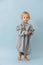 Handsome toddler boy in a huge oversized grey longsleeve over blue