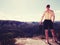 Handsome topless hiker looking at horizon with high Sun