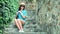 Handsome traveler woman sitting on stairs with stone steps smiling and playing with hair