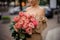 Handsome woman holds lovely bouquet of stylish bright peony roses