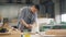 Handsome woodworker using polishing machine to polish wood in workshop