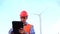 Handsome worker at wind turbine power plant with tablet in hand on sky background