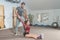 Handsome yoga male personal trainer with a beard helping young fitness girl to stretch her muscles after hard training workout, re