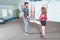 Handsome yoga male personal trainer with a beard helping young fitness girl to stretch her muscles after hard training workout, re