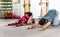 Handsome yoga male personal trainer with a beard helping young fitness girl to stretch her muscles after hard training workout, re