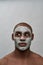 Handsome young african american man looking surprised aside, using facial blackhead removal mask, posing isolated over