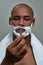 Handsome young african american man with shaving foam applied on his face holding steel razor, posing isolated over gray