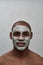 Handsome young african american man smiling at camera, using facial blackhead pore removal mask, posing  over