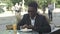 Handsome young afro american businessman using smart phone, messaging his girlfriend, eating at cafe