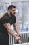 Handsome young bearded muscular man in black jersey rest relaxing in gym during hard workout training pause