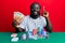 Handsome young black man playing poker holding 50 euros banknotes smiling with an idea or question pointing finger with happy