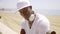 Handsome young black man seated on beach wall