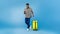 Handsome young black man with suitcase using mobile phone, booking summer vacation tourist trip over blue background