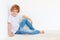 Handsome young boy, kid sitting near the white wall