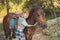 Handsome Young boy with red hair and blue eyes playing with his friend horse pony in forest.Huge love between kid shild and animal