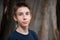 Handsome young boy at summer park. Beautiful calm smiling teen boy against nature background