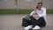 Handsome young businessman in glasses talking on the phone outdoors while sitting on the ground at the street