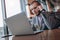 Handsome young businessman in jacket with a beard is sitting in cafe with laptop