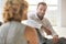 Handsome young businessman smiling while sitting on the floor with collegues in new office