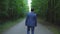 Handsome young businessman walking along the road in forest, view back