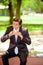 Handsome young businessman wearing a suit and doing a huge bite eating a sandwich at outdoors, in a blurred park