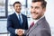 Handsome young businessmen shaking hands and smiling at camera