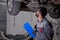 Handsome young caucasian auto mechanic in uniform is making notes while examining car in auto service