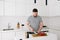 Handsome young caucasian man cooking a nice healthy vegetable meal or salad in a modern bright white kitchen