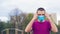 Handsome young caucasian man in a pink T-shirt and blue medical mask on a background of trees. The guy puts on a medical mask