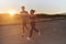 A handsome young couple running together during the early morning hours, with the mesmerizing sunrise casting a warm