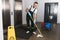 handsome young janitor mopping floor and smiling