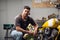 A handsome young male biker in his garage is preparing his motorcycle for the season. Repair and tuning.