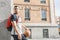 Handsome young man with a basketball and a backpack on his back looks aside while leaning on a column