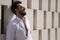 Handsome young man with beard, sunglasses and open white shirt, leaning against a wall of white stone blocks, smiling in sexy