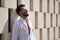 Handsome young man with beard, sunglasses and open white shirt, leaning against a wall of white stone blocks, smiling in sexy